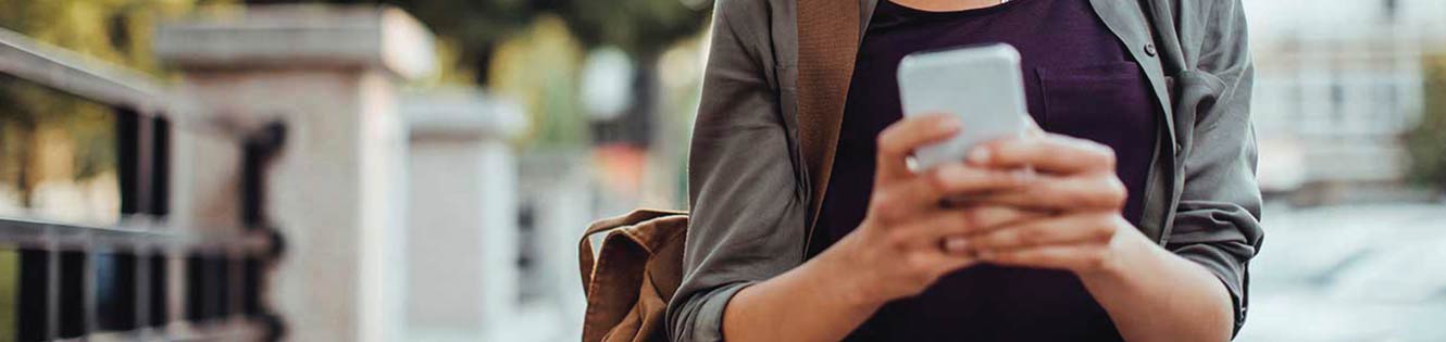 Person using a smart phone to bank while walking on the sidewalk.